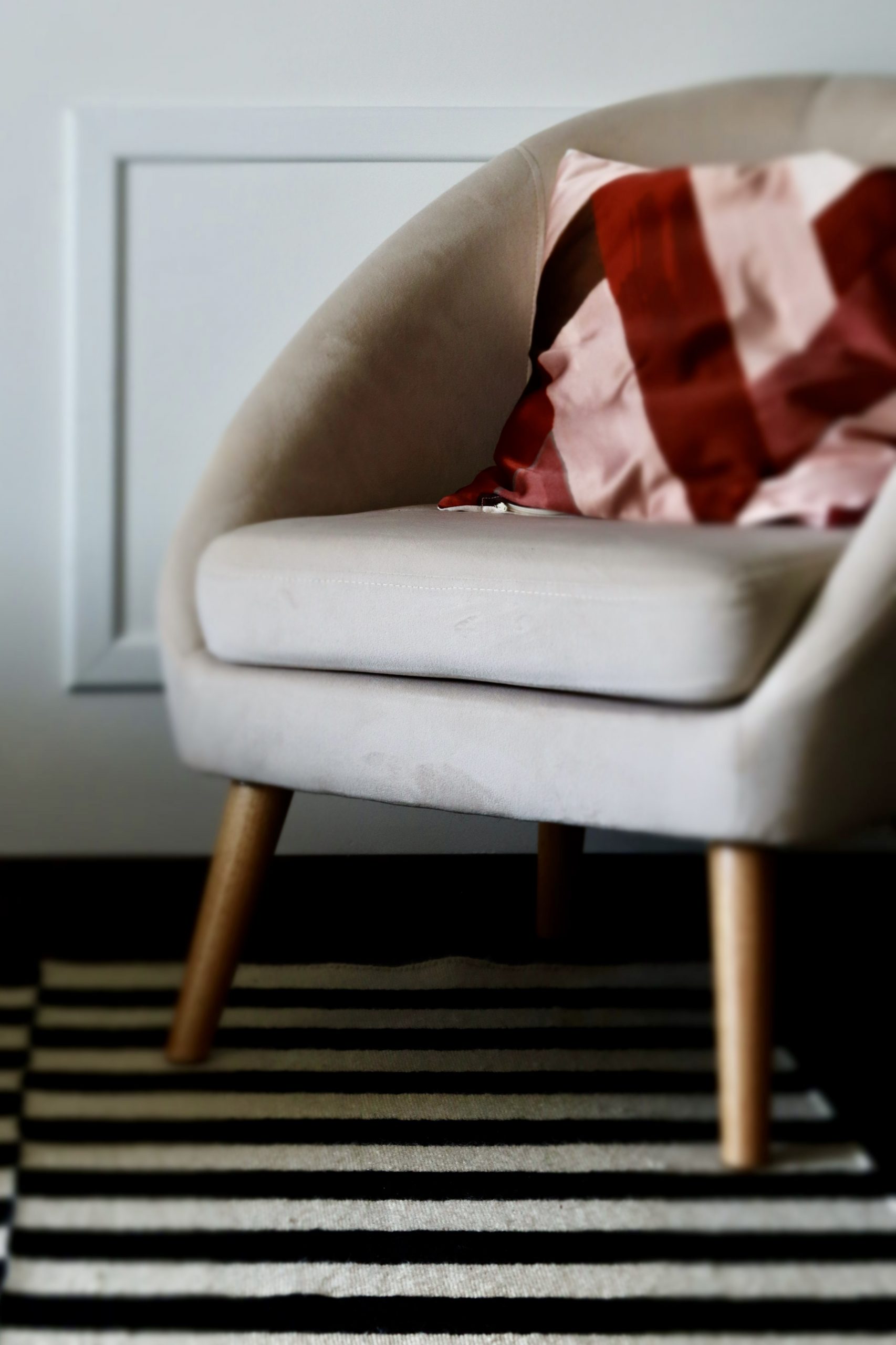 Projet Georges - fauteuil gris avec coussin rouge, tapis rayé noir et blanc