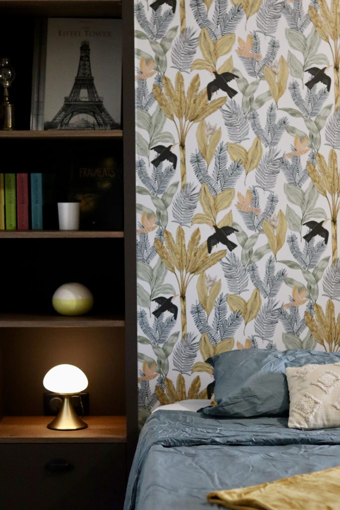 Projet Charlie - chambre avec étagère en bois, lit et lampe, papier peint fleuri